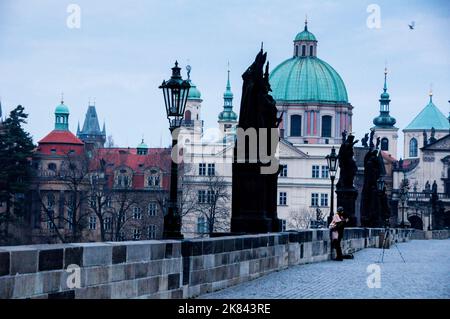 Charles Bridge Baroque statues silhouette against the blue-green of the dome of St. Francis of Assisi Church in Prague, Czech Republic. Stock Photo