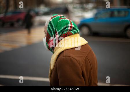 Old woman in coat. Russian grandmother in autumn. Warm scarf on head. Poor man in Russia retired. Stock Photo