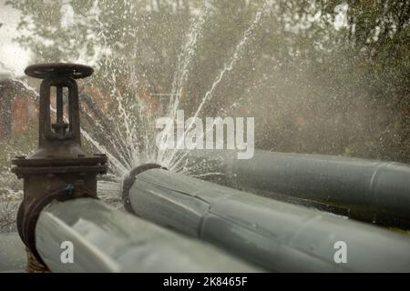 Breakthrough heating pipe. Pipeline accident. Boiling water pours out. Loss of tightness. Stock Photo