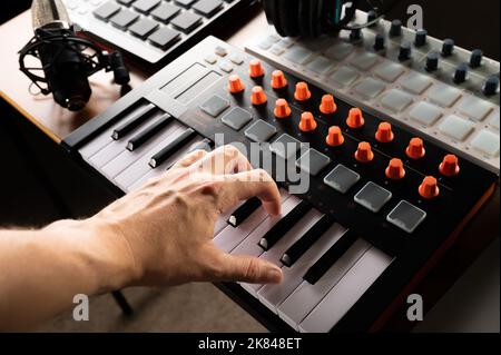 Studio equipment for recording studio, music studio. Musician's hand on midi keyboard. Studio headphones. Recording a music album, podcast. Advertisin Stock Photo