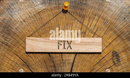 The word Fix is written on the wooden surface. wooden surface in background. Stock Photo