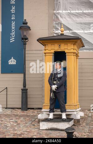 Sweden, Stockholm - July 16, 2022: Royal Palace. Closeup of male armed guard at entrance. Stands in front of small yellow shelter. Lantern in back Stock Photo