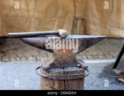 Rusty old anvil and hammer on a wooden stand Stock Photo