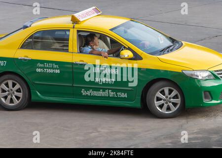 SAMUT PRAKAN, THAILAND, OCT 03 2022, The taxi driver smokes from the open window while driving Stock Photo