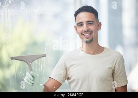 Clean windows make me happy. a young man cleaning a glass window at home. Stock Photo
