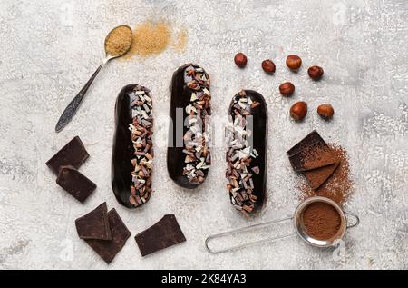 Composition with tasty chocolate eclairs and ingredients on light background Stock Photo