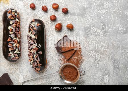 Tasty chocolate eclairs and hazelnuts on light background Stock Photo
