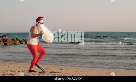Santa Claus summer vacation. Santa Claus having fun. Funny Santa, in sunglasses and flippers, is dancing on beach by the sea and relaxing. Santa going to snorkel. High quality photo Stock Photo