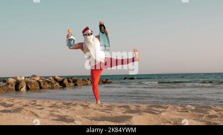 Santa Claus summer vacation. Father Christmas, having fun. Santa Claus doing yoga. Funny Santa, in sunglasses, with flippers and snorkeling mask, on beach by the sea. Santa going to snorkel. High quality photo Stock Photo
