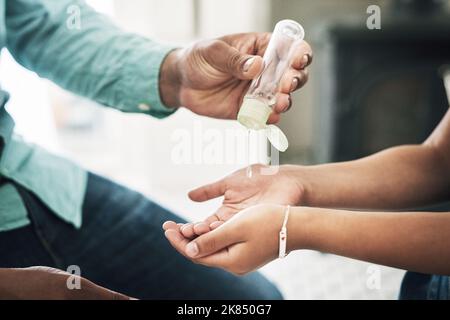 Teach your children about hygiene. two unrecognizable people using hand sanitiser at home. Stock Photo