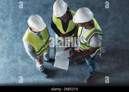 Everything seems to be in order on paper. High angle shot of a group of contractors standing in the warehouse together and having a discussion. Stock Photo