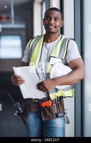 The design rests in my hands now. a handsome young contractor standing alone in a building and holding the floor plan. Stock Photo