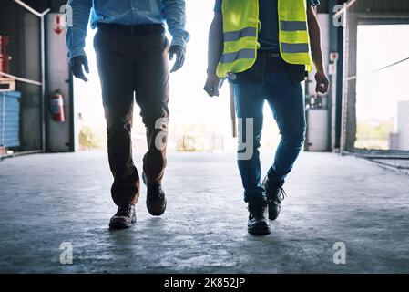 Progress is a process. two unrecognisable builders walking through a construction site. Stock Photo