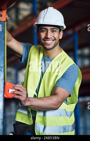 I take pride in the work I provide. a young builder using a measuring tape at a construction site. Stock Photo