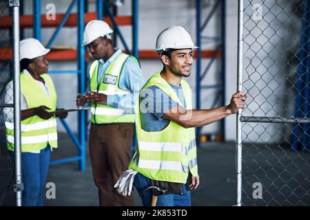 Back in business and back in action. a young builder opening the gates to a construction site. Stock Photo