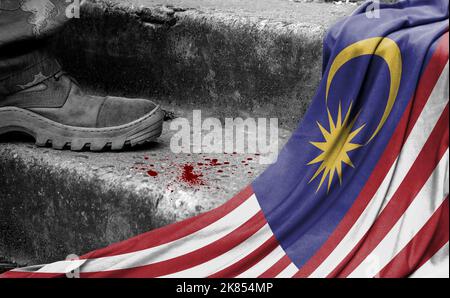 The leg of the military stands on the step next to the flag of Malasia, the concept of military conflict Stock Photo
