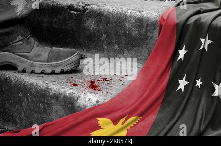 The leg of the military stands on the step next to the flag of Papua New Guinea, the concept of military conflict Stock Photo