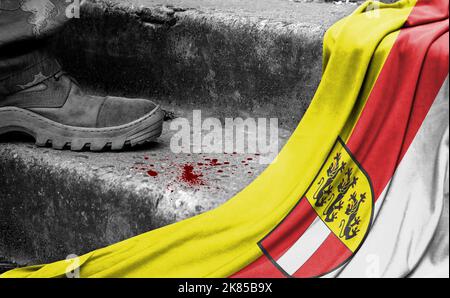 The leg of the military stands on the step next to the flag of Carinthia, the concept of military conflict Stock Photo