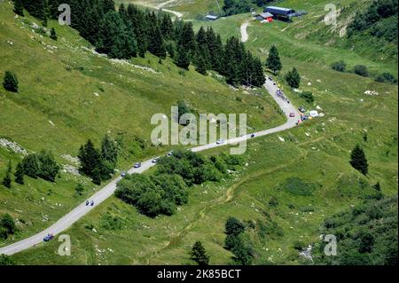 Col de la Madeleine looking down on the peloton and breakaway bunch as they do the first climb of the day with helicopters and fans surrounding them, Stock Photo