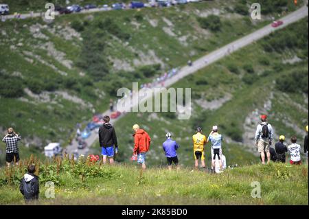 Col de la Madeleine looking down on the peloton and breakaway bunch as they do the first climb of the day with helicopters and fans surrounding them, Stock Photo