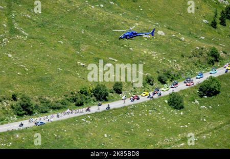 Col de la Madeleine looking down on the peloton and breakaway bunch as they do the first climb of the day with helicopters and fans surrounding them, Stock Photo