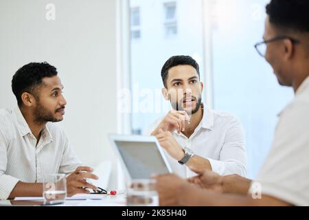 Discussing options and ideas. a group of young diverse businessmen having a meeting in the boardroom. Stock Photo