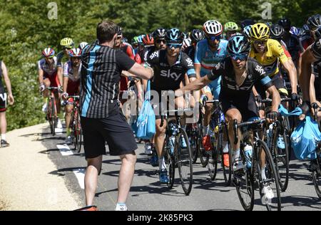 Richie Porte misses his water bottles and energy gels as a soigneur deals them out on the first climb Stock Photo