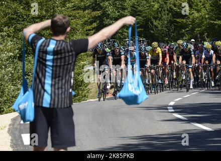 A soigneur hands out energy gels and water bottles on the way up the first climb from Bourg de Peage and Gap.   Stock Photo