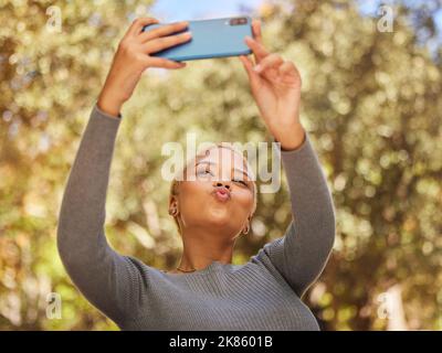 Black woman, phone and selfie with pout in park with sunshine, summer and happiness by trees. Woman, smartphone and lips in kiss for photo, outdoor Stock Photo