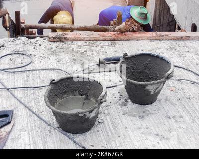 Cement tank for mixing mortar at a construction site with construction workers plastering the stairs Stock Photo