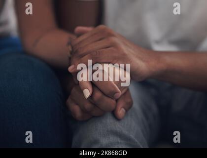 Were determined to make this love work. an unrecognizable couple sitting inside together and holding hands. Stock Photo