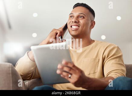 Phone call, tablet and man networking, speaking and working on the internet from the sofa in his house. Happy, thinking and young freelancer speaking Stock Photo