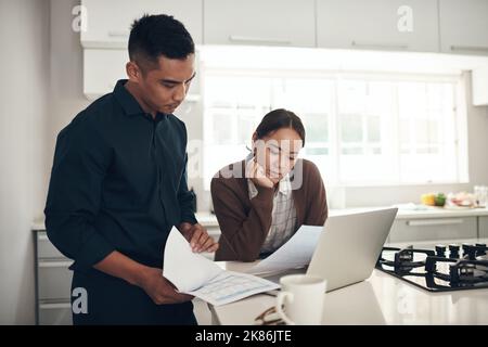 Planning for financial security. a young couple going through paperwork while using a laptop at home. Stock Photo