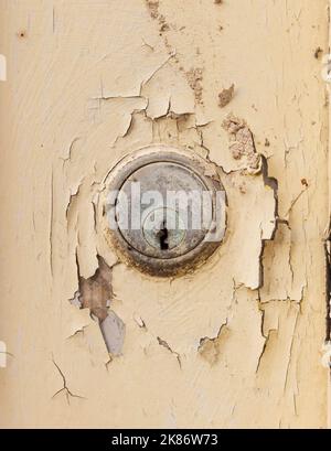 Close up of a worn Yale lock on an old wooden door with flaking paint. UK Stock Photo