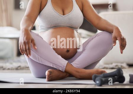 Staying fit for the two of us. a pregnant woman doing yoga at home. Stock Photo