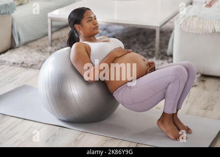 Staying active during my pregnancy is the best decision Ive made. a beautiful young pregnant woman exercising at home. Stock Photo