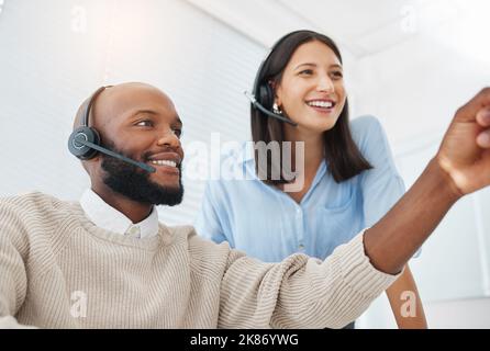 Look at that. a handsome young salesman sitting in the office and wearing a headset while getting help from his manager. Stock Photo