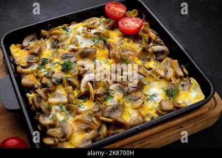 Omelet with mushrooms, onions and dill, in a frying pan Stock Photo