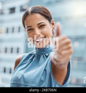 All the best in your new business venture. a young businesswoman showing thumbs up against an urban background. Stock Photo