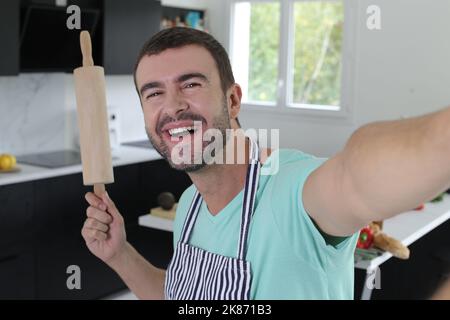 Man taking selfie with rolling pin in the kitchen Stock Photo
