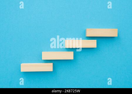 Four wooden small planks, long shape with blank surface growing up on blue background, for business concept ideas Stock Photo
