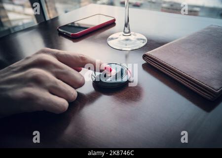 Female hand finger presses the button to call the waiter in the restaurant to pay for food for dinner. Pressing the buzzer. Good Tips. Stock Photo