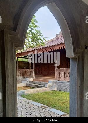 front view of a traditional Javanese wooden house framed by a concrete gate Stock Photo