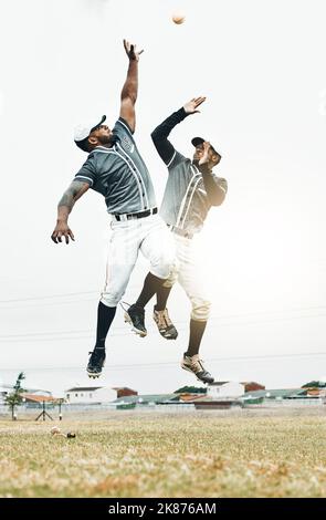 Baseball player, jump and catch baseball in game, contest or sport on field for sunshine. Team, teamwork and hands for ball in air at stadium, arena Stock Photo