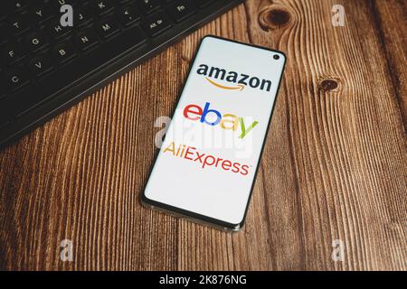 Amazon, Ebay, Aliexpress app logos on smartphone screen and black keyboard on wooden background. Dropshipping concept. Swansea, UK - March 19, 2021 Stock Photo
