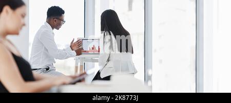 Turning to the stats for further insights. Rearview shot of businesspeople analysing graphs on a laptop in an office. Stock Photo