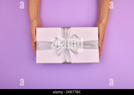 Hands holding blue gift box pink background Stock Photo