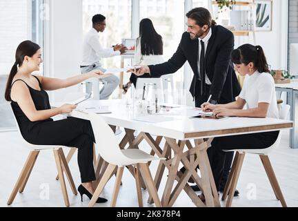 Ensuring their reports stay up to date. businesspeople passing paperwork to each other while working in an office. Stock Photo