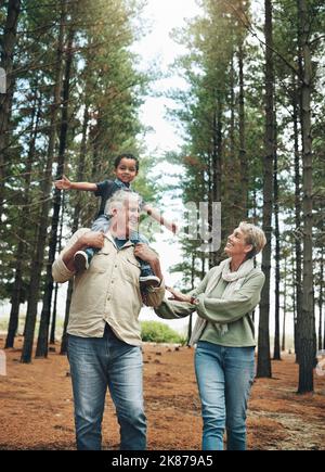 Hike, nature and children with senior foster parents and their adopted son walking on a sand path through the tress. Family, hiking and kids with an Stock Photo