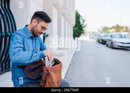 Relaxed adult man, preparing to work outside, getting his laptop ready for the job. Stock Photo